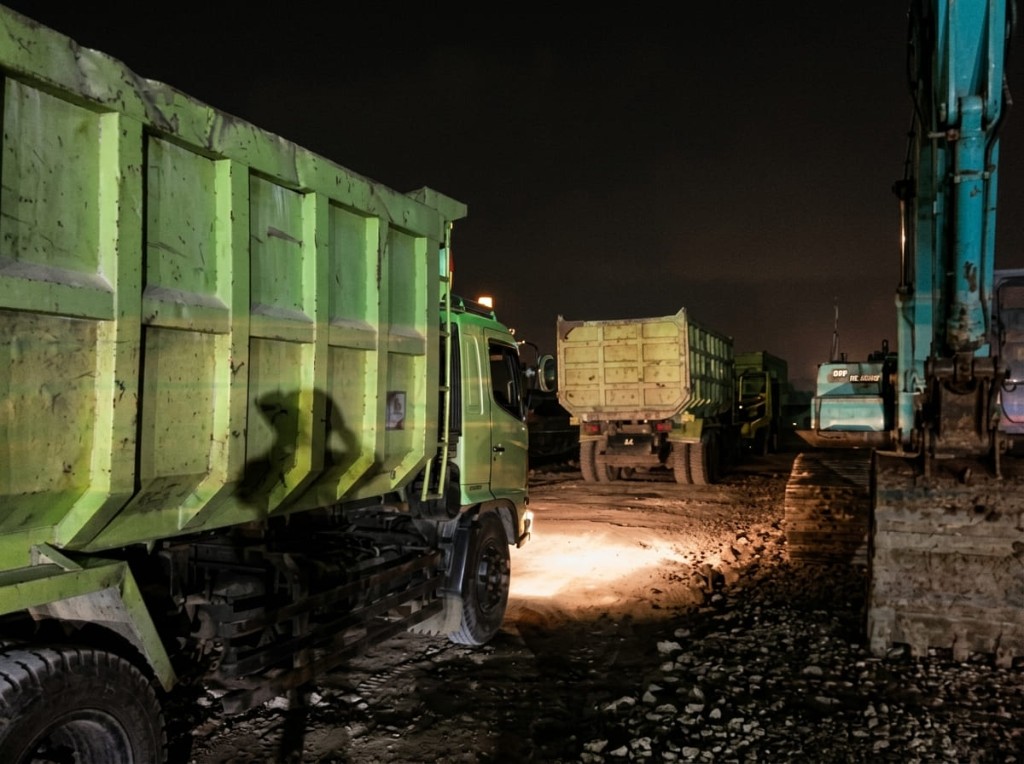 Dump truck dan ekskavator pada shift malam.