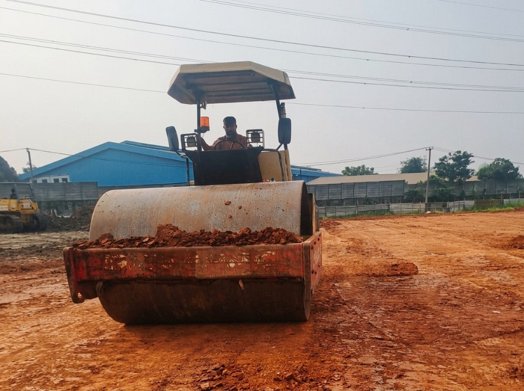 Roller memadatkan tanah merah.