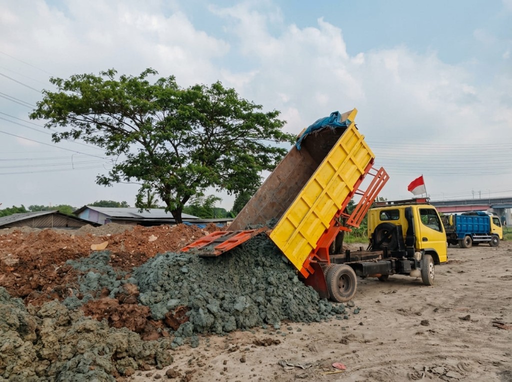 Dump truck menuang urugan.